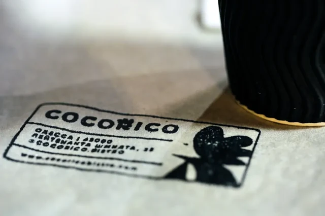 Чёрная печать Cocorico на светлой бумаге рядом со стаканом — ИЗДИДЖИТЛ